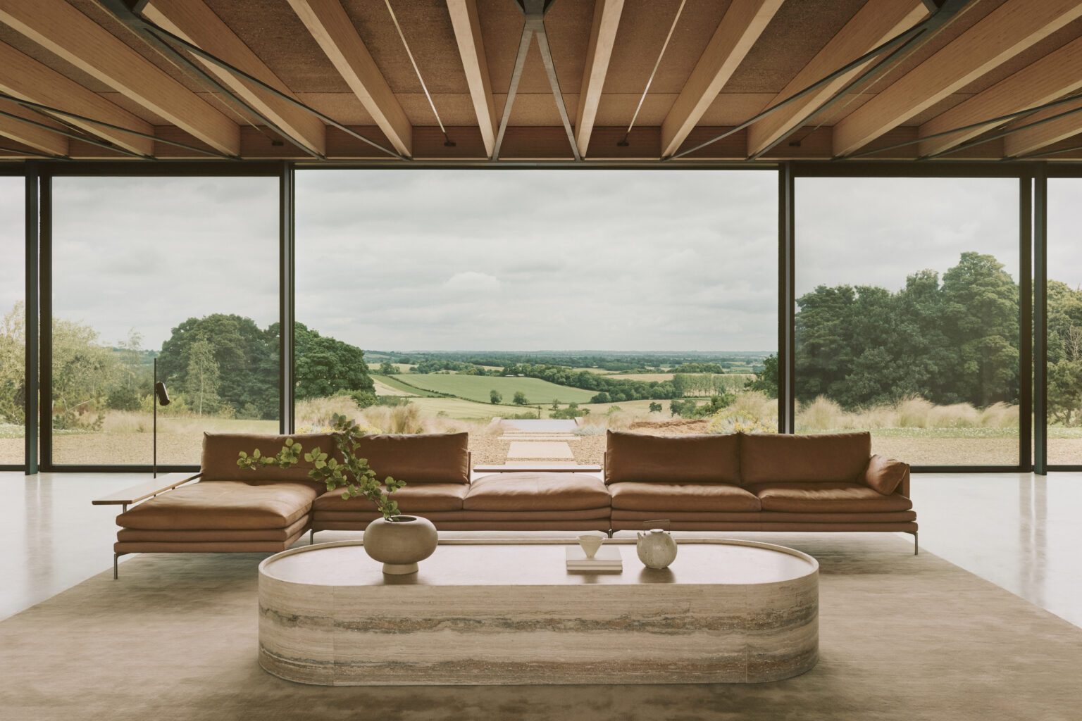 A glass-walled living room opening onto rolling English farmland